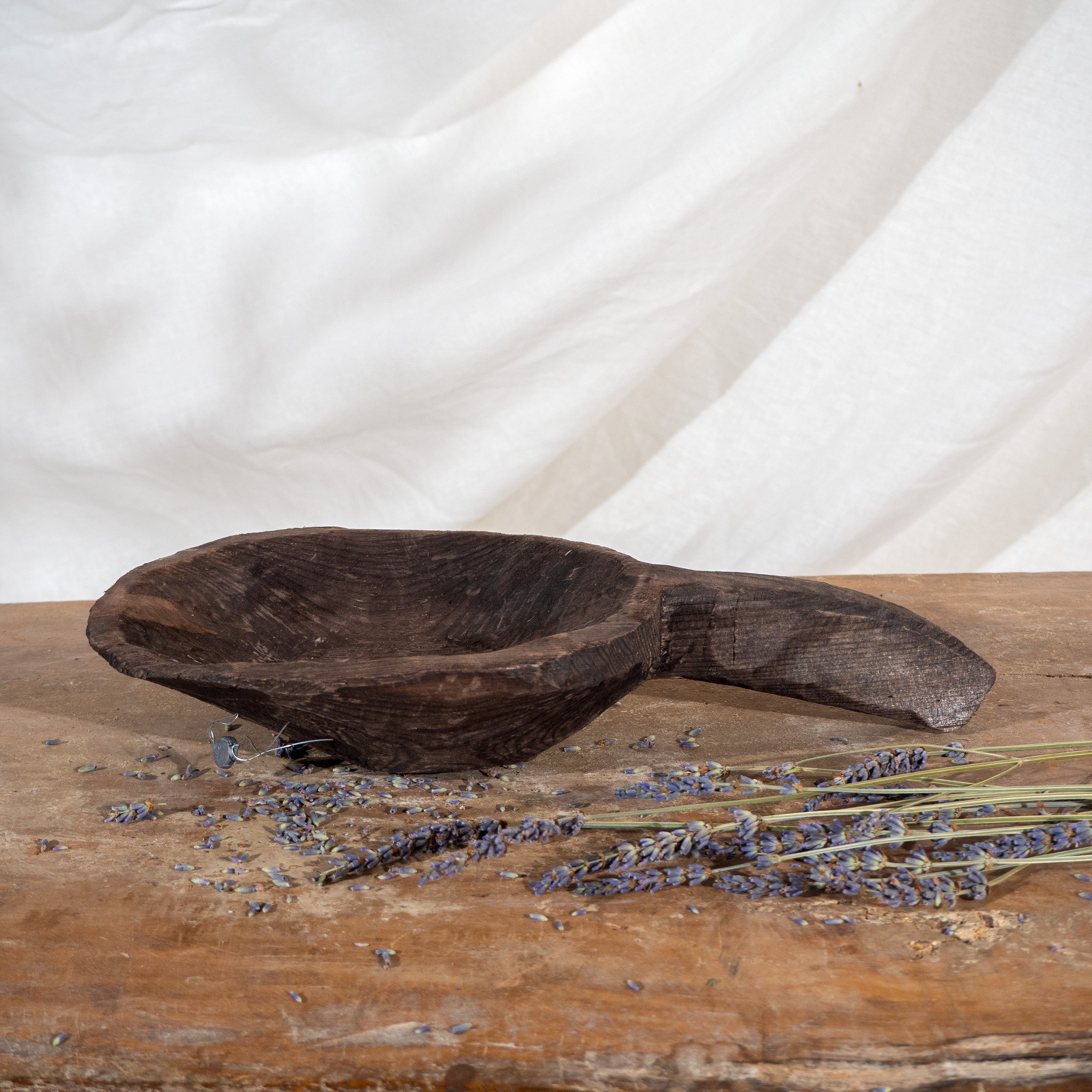 Vintage carved wooden spoon boat with handle on vintage bench with dried flowers