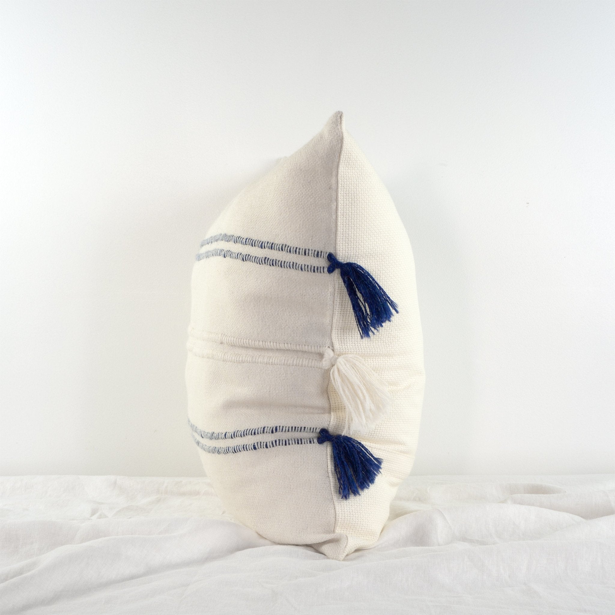 Handwoven white and navy blue baby alpaca cushion from Peru on a table side on