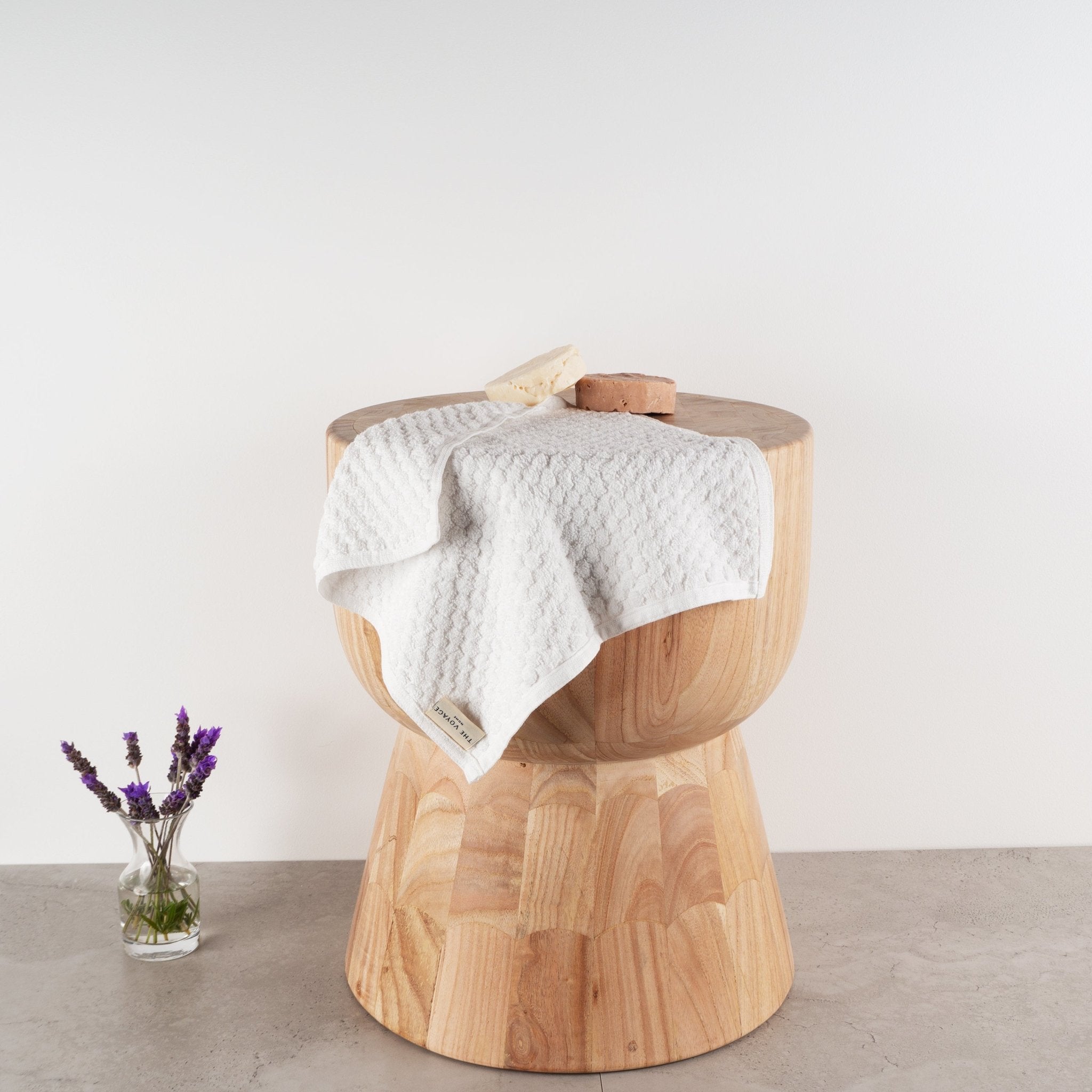 Handloomed organic cotton Turkish face towel in white grid pattern draped over wooden stump with lavender